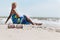 Sunglasses on the sand and beautiful woman with blue sarong