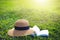 Sunhat and book lying on a lush green garden lawn under the hot rays of the sun