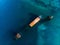 Sunken cargo ship near coast of sea city, large abandoned rusty vessel in water, aerial view