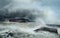 A sunken old ship with a tanker on its side stranded on the seashore amidst giant waves. dramatic sky and stormy sea.