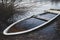 Sunken rowing boat lies on the shore of a frozen small lake