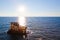 Sunken rusty cargo ship in still blue sea waters with bright sun