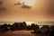 sunlight from behind clouds with rocks boat on foreground