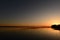 Sunlight in the blue sky from behind the cape shoreline of the lake at sunset