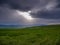 Sunlight breaking through the stormclouds over beautiful green meadow