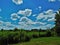 Sunlight clouds over a gate and a meadow