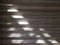 Sunlight falls on fabric blinds in the form of a corrugated sheet with horizontal stripes of gray color.