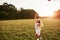 Sunlight goes above the trees. Happy girl in white clothes have fun with kite in the field. Beautiful nature