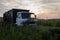 Sunlight reflects through window of old dump truck on grass field at sunrise