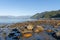 Sunlight on rocky foreshore as sun sets across Jackson Bay