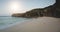 Sunlight sand beach at ocean bay waves aerial view. Amazing seascape with cliff coast and stones