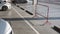 Sunlight and shadow on surface of steel red and white traffic barrier with row of concrete wheel stops and white marking lines on