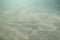 Sunlight shining through the ocean surface and reaching the sea bed as sand is dragged up by the current