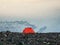 Sunlight slides across the surface of the glacier early in the morning. Camping high in the mountains. An orange tent on a rocky