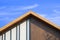 Sunlight on surface of vintage wooden gable roof with battens decoration against cloud on blue sky background