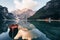 Sunlight is on the top. Wooden boat on the crystal lake with majestic mountain behind. Reflection in the water. Chapel