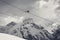 Sunlit chair lift, snowy ski slope, high winter mountains and cloudy sky