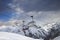 Sunlit chair lift, snowy ski slope, high winter mountains and dark cloudy sky