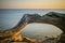 Sunlit curved tree trunk against the sea at sunset in summer.