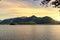 Sunlit Derwentwater lake surface with a greeny mountain range behind seen through tree branches