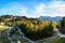 Sunlit forest with cable car and rocky mountains in the background. In the distance is the Vogel peak in the Julian Alps in summer