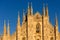 Sunlit front facade of Duomo di Milano at dusk