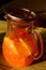 Sunlit glass jar with fresh orange juice, spoon and stainless strainer