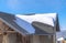 Sunlit gray pitched roof of a home with mound of fresh snow at winter season