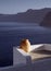 Sunlit Greek Urn in Oia town on the Greek Island of Santorini with blue sea and mountains in background