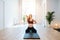 Sunlit image of a pregnant woman sitting on a mat, practicing yoga alone