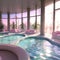 A sunlit indoor lounge area with a pool - 1