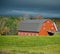 Sunlit Red Barn and Stormy Skies