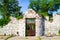 Sunlit Ruins of a Stone Structure with Locked Gate in Lush Greenery