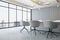 Sunlit stylish conference room with modern meeting table and chairs around, city skyline view from panoramic window and grey