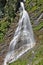 Sunlit waterfall in the Austrian Alps with rainbow long time exposure