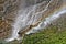 Sunlit waterfall in the Austrian Alps with rainbow long time exposure