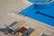 Sunlounger chairs near a pool with blue water and chrome grab bars