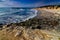 Sunny afternoon deserted beach with overhanging cliffs and gentle waves