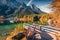 Sunny autumn view of Hintersee lake with wooden pier and fishing boat.