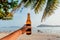 Sunny beach and beer bottle in hand of happy tourist during holidays. Ocean view with fresh beer of a vacationist