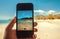 Sunny beach on screen of smartphone. Ocean view and picture of sand in hand of tourist Happy vacation