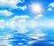 Sunny day background, blue sky with white cumulus clouds and glaring sun over sea water