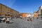 A sunny day with a blue sky in the ancient Piazza Navona as tourists sightsee and wander past street artists selling their artwork