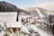 Sunny day at the Bukovel ski resort. Alley of wooden houses and cars parked, snowy mountains and ski slopes