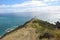 Sunny day at Cape Reigna with people  hiking up to the white lighthouse, New Zealand