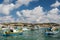 Sunny day of fishermen village with colorful boats of Malta. Mediterranean landscape under white clouds