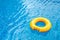 Sunny day at the pool.Bright yellow float in blue swimming pool, ring floating in a refreshing blue swimming pool with waves