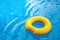 Sunny day at the pool.Bright yellow float in blue swimming pool, ring floating in a refreshing blue swimming pool with waves