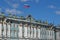 Sunny day in Saint-Petersburg, russian flag flying above facade of Hermitage State Museum