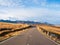 Sunny highway to the snow-capped peaks. Autumn morning deserted highway. Beautiful asphalt freeway, motorway, highway through of